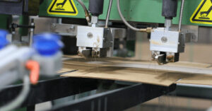 Properly aligned patterns on a hot melt adhesive dispensing unit applying adhesive to a cardboard substrate.