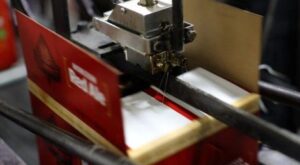 Adhesive packaging solutions: dispensing nozzle sealing a carton flap